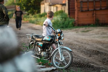 Vladimir / Rusya / 2020: Korkmuş çocuklar kütüklere oturup ateşe bakarlar, kız ağlar