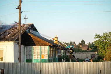 Acil durum bakanlığı formundaki itfaiyeciler çatıdaki yangını söndürüyorlar.