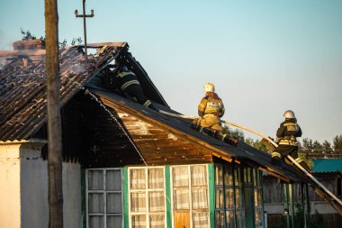Acil durum bakanlığı formundaki itfaiyeciler çatıdaki yangını söndürüyorlar.