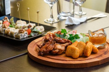 Tavuklu mezeler, nugget ve ahşap tabakta soslu rulo köfte.