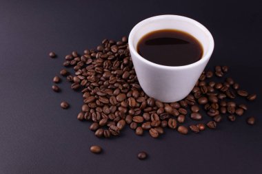 Kahve çekirdeğinin içinde espresso dolu beyaz masa takımı.