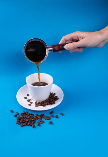 Wlać kawę w filiżance na tle ziaren kawy — Zdjęcie stockowe