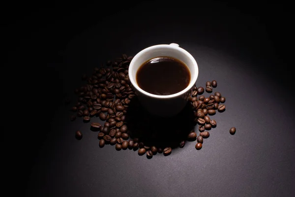 Чашка кофе и кофейные бобы вокруг освещаются сверху l — стоковое фото