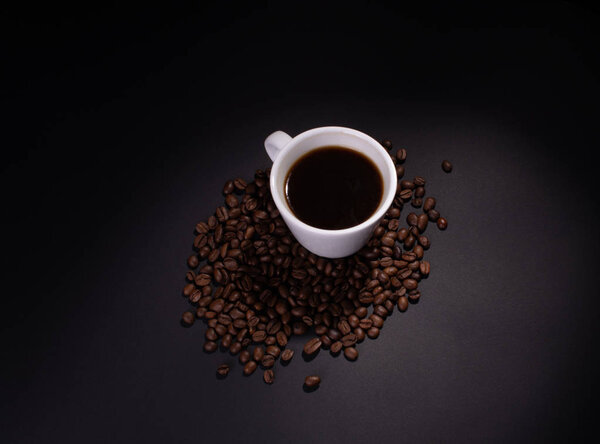 Coffee beans and a cup of coffee in soft top lighting
