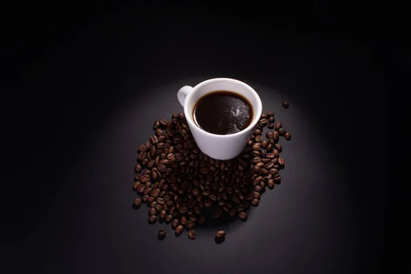 Полная чашка кофе и кофейные бобы зажигаются сверху . — стоковое фото