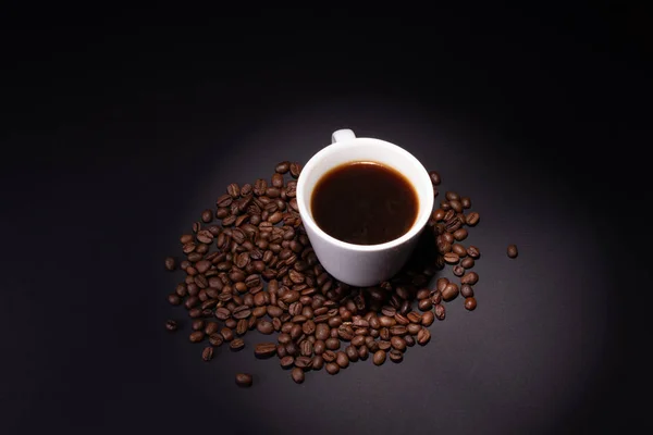 Filiżanka parzonej kawy wśród ziaren kawy na ciemnym podłożu — Zdjęcie stockowe
