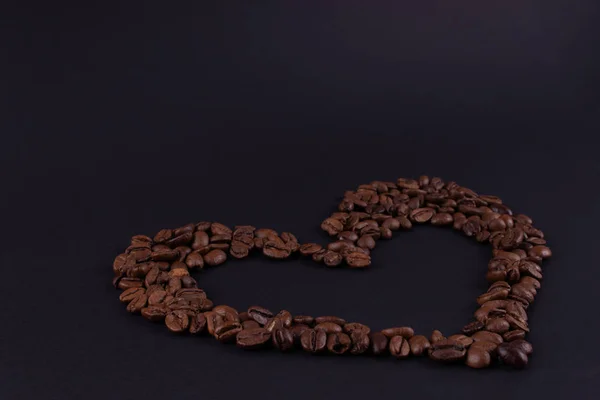 Кофе в форме сердца на темной бумаге — стоковое фото