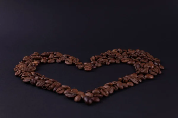 Большое сердце кофейных зерен на темной поверхности — стоковое фото