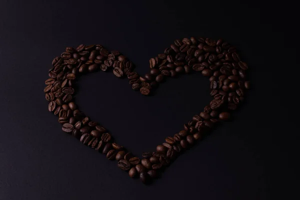 Heart lined with grains of coffee on a dark background top view — Stock Photo, Image