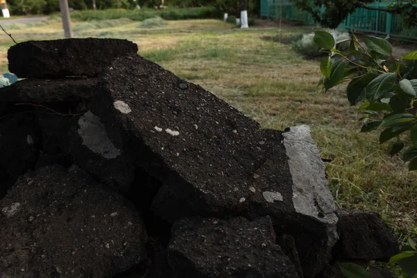 Куча сломанного черного асфальта лежит в саду рядом с домом — стоковое фото