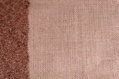 Koyu kahverengi keten tohumları yoğun bir kumaş üzerinde uzanıyorlar.