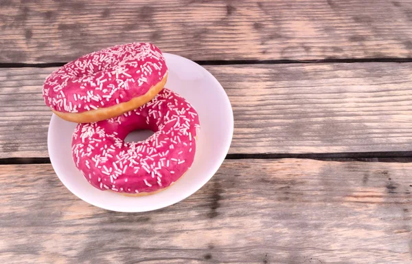 Une composition de deux beignets roses glacés avec des saupoudres blanches dans — Photo