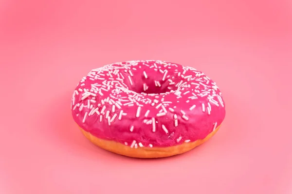 A close-up side view of one isolayed pink donut on pink backgrou — Stock Photo, Image