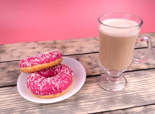 Vue latérale d'une tasse de cofee avec du lait et deux beignets roses sur un w — Photo