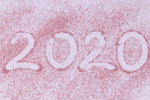 2020 yıllık tarih, pembe kumlara serpilmiş bir parmakla yazılmış. — Stok fotoğraf