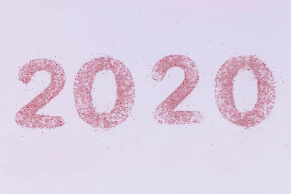 2020 número hecho de pequeñas partículas de arena rosa sobre fondo blanco —  Fotos de Stock