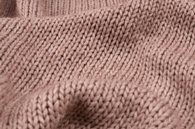 Açık bej örülmüş yatak örtüsü. Yüzeyde dağınık bir şekilde yatıyor.