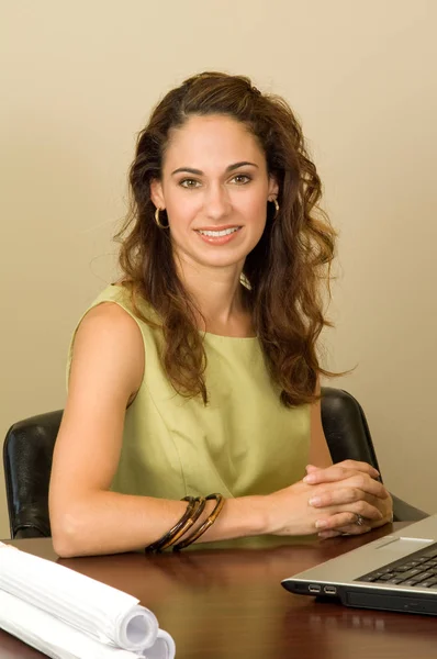 A pretty brunette business professional wearing a green outfit.