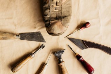Eski moda ayakkabıcı aletinin ve kahverengi derinin üzerinde duran eski model ayakkabının üst görüntüsü 