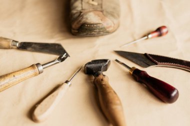 Eski moda ayakkabı imalatçısının aletinde alçak açılı görüş ve kahverengi deri üzerinde duran eski model ayakkabı. 