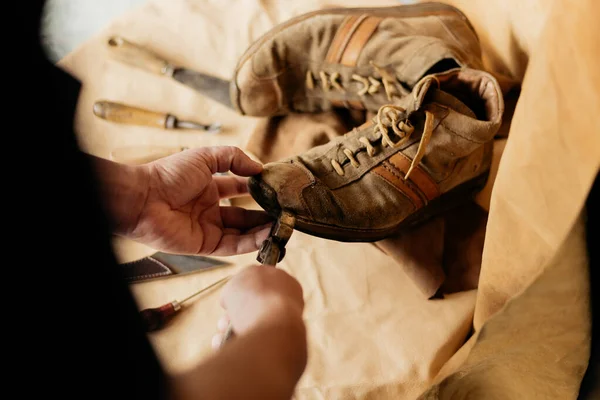 Cobbler repairing an old leather shoe. Male shoemaker using pliers on dirty boot.