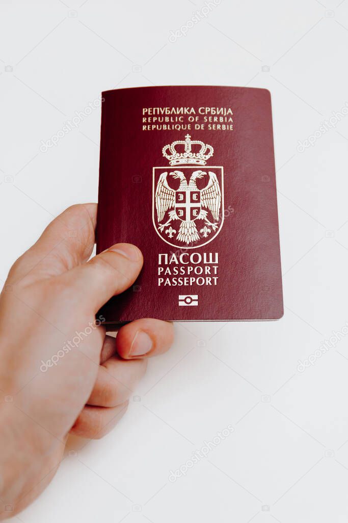 Hand holding Serbian biometric passport, isolated on white background