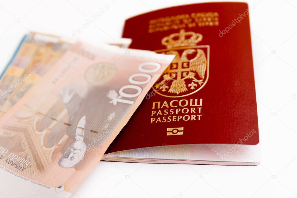 Serbian biometric passport with pile of paper money around, isolated on white background