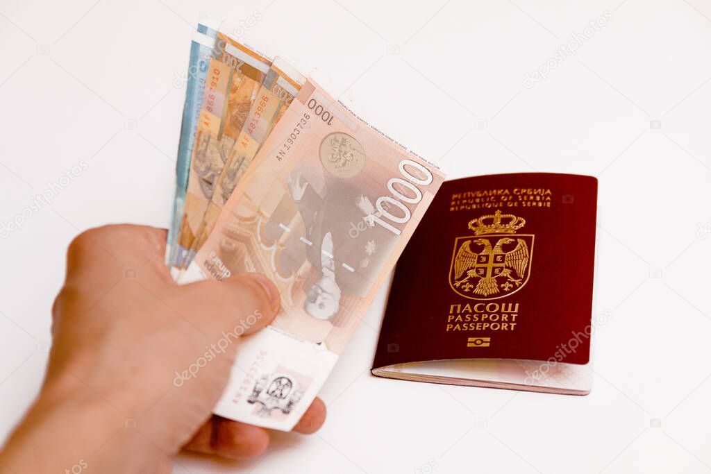 Hand holding Serbian paper money and Serbian biometric passport on white background