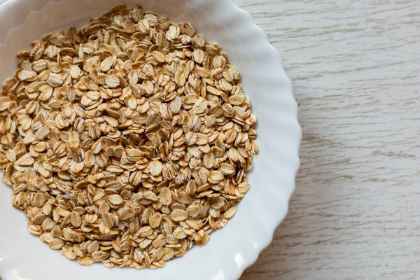 stock image Table top view of bowl of dry oats on wooden table