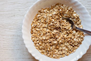 Tahta masadaki bir kase kuru yulaf. Kase sağ tarafta.. 