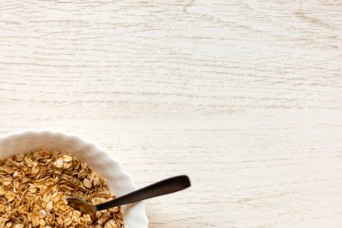 Tahta masadaki bir kase kuru yulaf. Kase sol alt köşede.. 