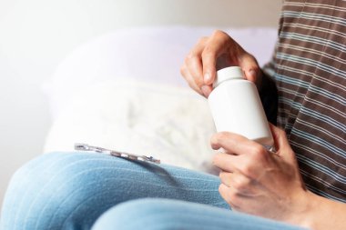 Beyaz şişeyi ilaçla açan adam, parlak doğal ışık, kapat.