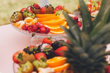 Meyve yemek masası. Taze portakal, çilek, kiraz ve ananas tabakta servis edilir.. 
