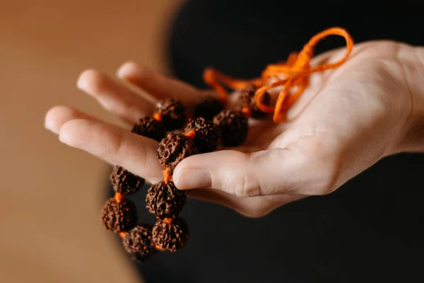 Rudraksha beads necklace in woman's hand, close up