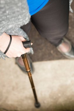 Kadının elinin ayaklı sopayla desteklendiği pozu yakın ve aşağı çek.