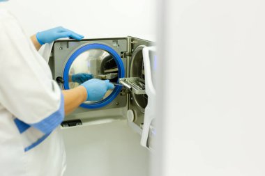 Otoklavyede diş aletleri sterilize ediliyor, eldiven ile yan görünüm.