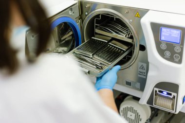 Otoklavda diş aletleri sterilize ediliyor. Omuz manzarası üzerinde eldiven var.
