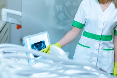 Kadın dişçi, film aydınlatıcısı (izleyici) kullanarak çene ve diş röntgenini gösteriyor. Diş hekimliği. 