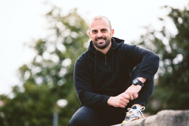 Dışarıda oturan ve gülümseyen aktif, yakışıklı bir adamın portresi.