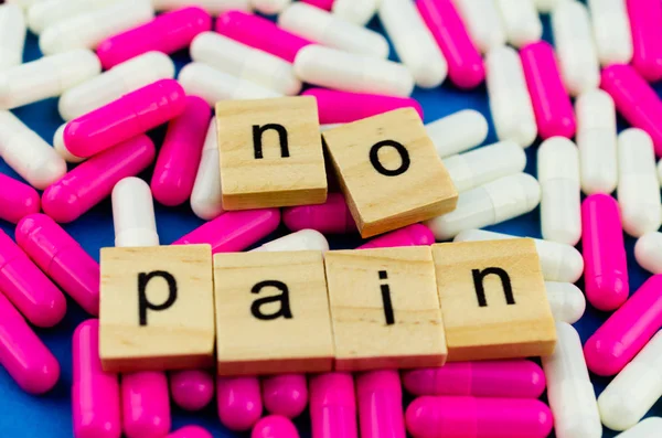 The word NO PAIN on the background of scattered pink and white capsules on a blue background