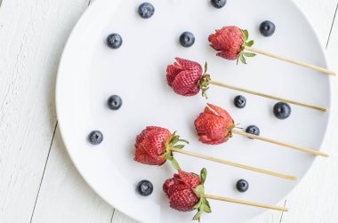 Meyve oymalar hazırlanması. Gül tomurcukları çilek. Şiş ile oyulmuş çilek. Taze meyve buzdolabında tazeliğini korumak için doğru sıcaklıkta tutulmalıdır
