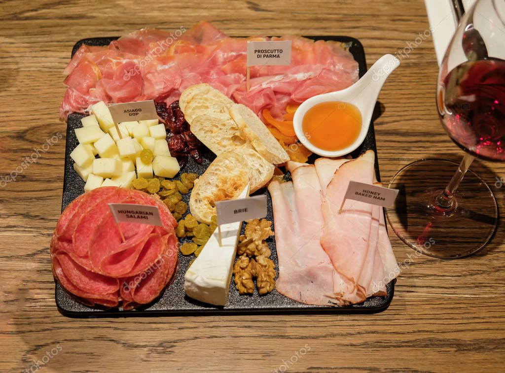 Carne curada y tabla de quesos servida con frutos secos, miel y frutos