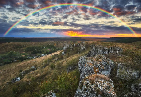 Rainbow with clouds over a rock