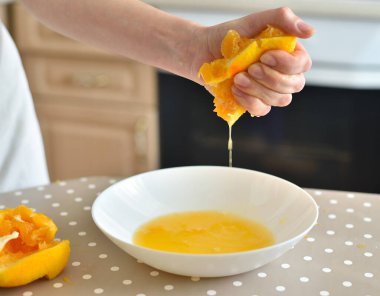 El portakalın suyunu sıkıyor.