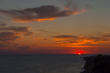 Gün batımı ve yanan bulutlar ve sakin deniz ile güzel bir deniz manzarası