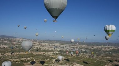 Kapadokya, Türkiye'de sıra dışı kayalık manzaranın panoramik manzarası. Renkli sıcak hava balonları Kapadokya bölgesinin derin kanyonları, vadileri ve peri bacaları üzerinde gökyüzünde uçuyor. 