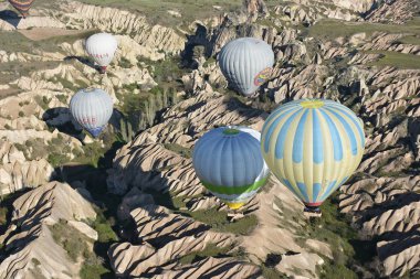 Kapadokya, Türkiye'de sıra dışı kayalık manzaranın panoramik manzarası. Renkli sıcak hava balonları Kapadokya bölgesinin derin kanyonları, vadileri ve peri bacaları üzerinde gökyüzünde uçuyor. 