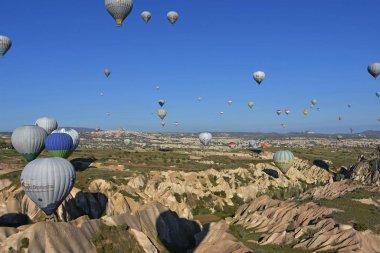 Kapadokya, Türkiye'de sıra dışı kayalık manzaranın panoramik manzarası. Renkli sıcak hava balonları Kapadokya bölgesinin derin kanyonları, vadileri ve peri bacaları üzerinde gökyüzünde uçuyor. 