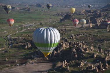 Kapadokya, Türkiye'de sıra dışı kayalık manzaranın panoramik manzarası. Renkli sıcak hava balonları Kapadokya bölgesinin derin kanyonları, vadileri ve peri bacaları üzerinde gökyüzünde uçuyor. 