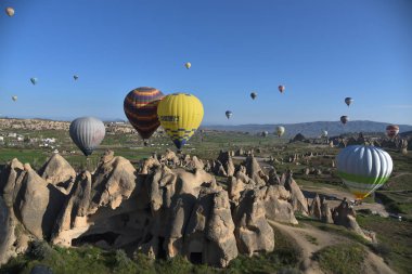 Kapadokya, Türkiye'de sıra dışı kayalık manzaranın panoramik manzarası. Renkli sıcak hava balonları Kapadokya bölgesinin derin kanyonları, vadileri ve peri bacaları üzerinde gökyüzünde uçuyor. 